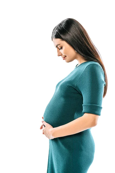 Vista lateral de niña embarazada sonriente tocando el vientre aislado en blanco - foto de stock