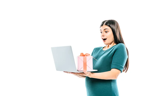 Choqué fille enceinte tenant ordinateur portable et cadeau isolé sur blanc — Photo de stock
