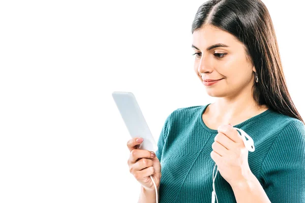 Sorridente ragazza incinta utilizzando smartphone e tenendo gli auricolari isolati su bianco — Foto stock