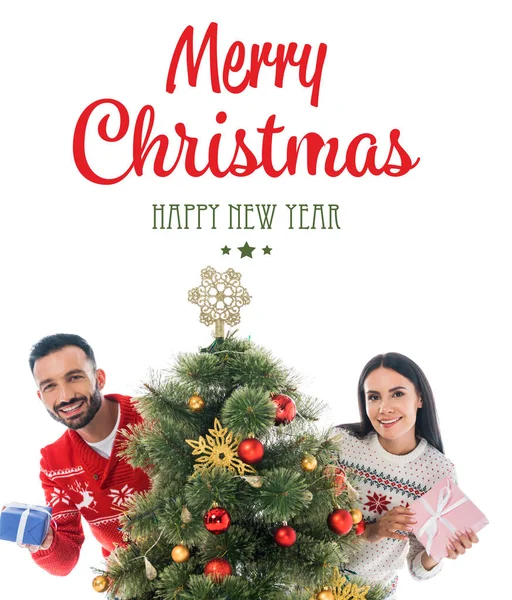 Glücklicher Mann und Frau mit Geschenken in der Nähe des Weihnachtsbaums isoliert auf weiß mit frohen Weihnachten und frohem neuen Jahr Schriftzug — Stockfoto