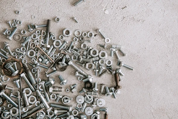 Top view of metal screws and nails scattered on grey background — Stock Photo