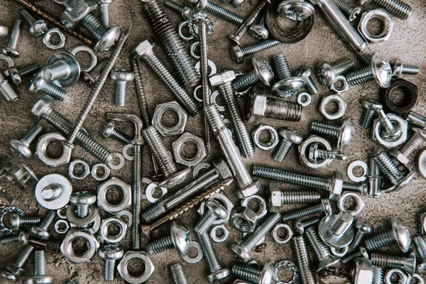 Top view of metal screws and nails scattered on grey background — Stock Photo