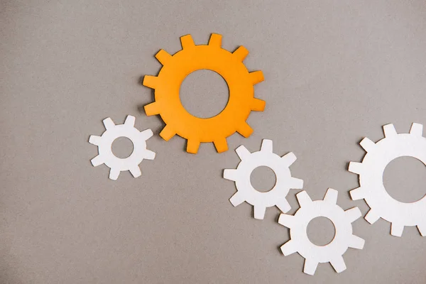 Top view of white and orange gears on grey background — Stock Photo