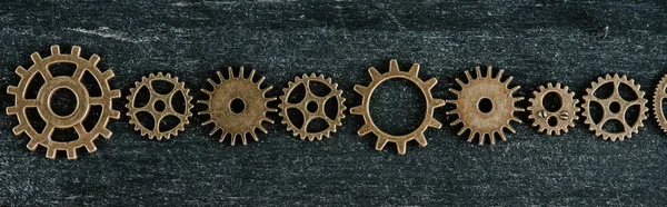 Flat lay with vintage metal gears on dark wooden background, panoramic shot — Stock Photo