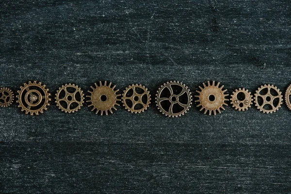 Flat lay with vintage metal gears on dark wooden background — Stock Photo