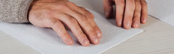 Vue recadrée de bind man lisant la police braille sur papier à table, prise de vue panoramique — Photo de stock