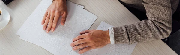 Cropped view of blind man reading braille font at table, panoramic shot — Stock Photo