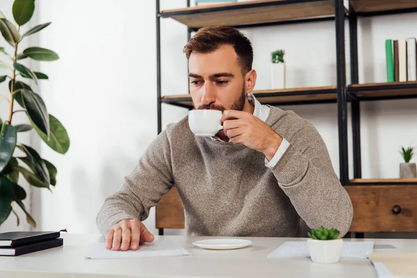 Слепой человек пьет кофе белое чтение за столом — стоковое фото