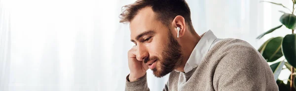 Side view of man using wireless earphones at home, panoramic shot — Stock Photo