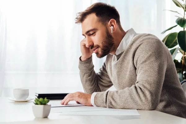 Side view of blind man reading and using wireless earphones at table — Stock Photo