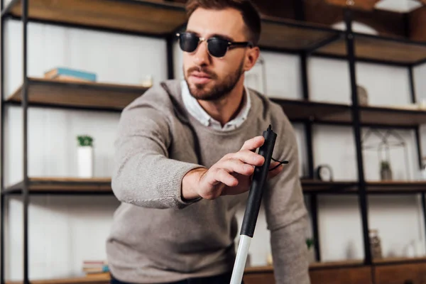 Selective focus of blind man holding walking stick in living room — Stock Photo