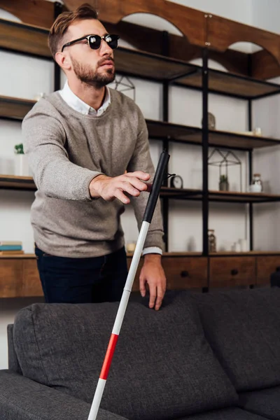 Blind man pulling hand to walking stick in living room — Stock Photo