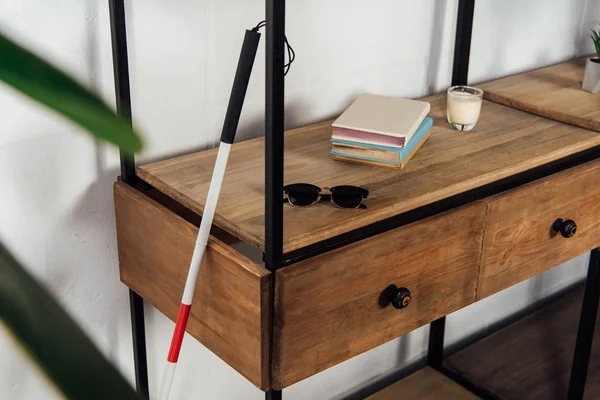 Walking stick beside sunglasses and books on cupboard shelf — Stock Photo