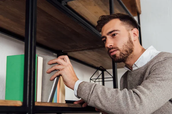 Blind man taking book from cupboard shelf — Stock Photo
