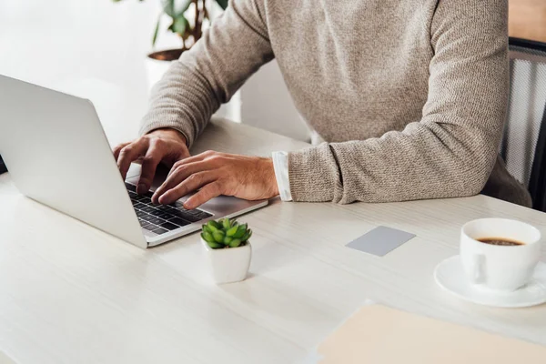 Cropped view of man typing on laptop keyboard beside card with copy space on table — Stock Photo