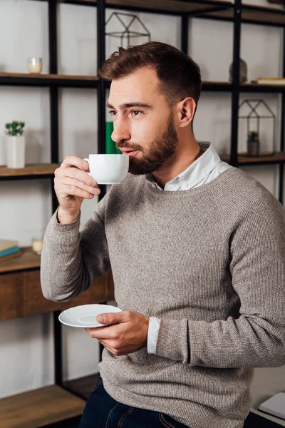 Красивый мужчина пьет кофе и смотрит в сторону дома — стоковое фото