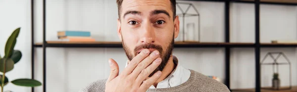 Aufgeregter Mann, der den Mund mit der Hand bedeckt und in die Kamera blickt, Panoramaaufnahme — Stockfoto