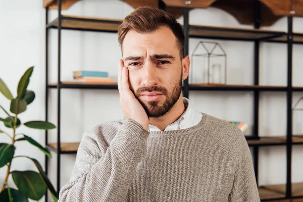 Worried man with hand beside face looking at camera — Stock Photo