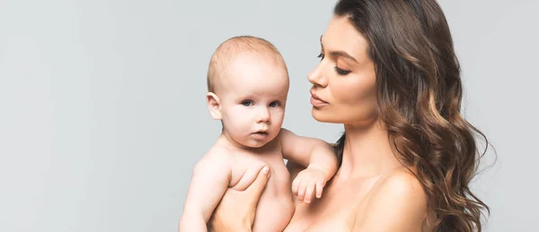 Plano panorámico de la joven madre desnuda abrazando bebé niño, aislado en gris - foto de stock