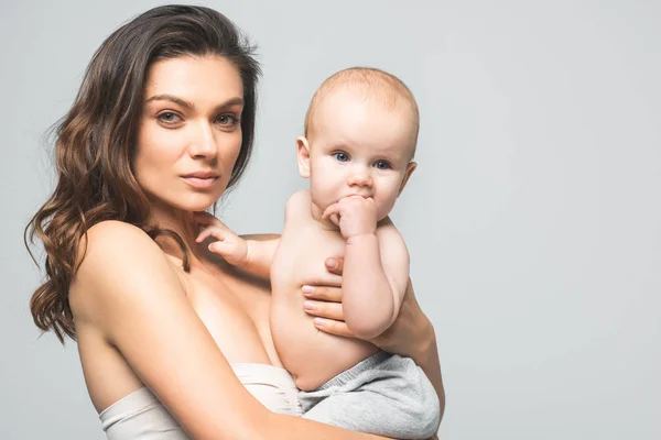 Porträt einer schönen Mutter, die einen kleinen Jungen hält, isoliert auf grau — Stockfoto