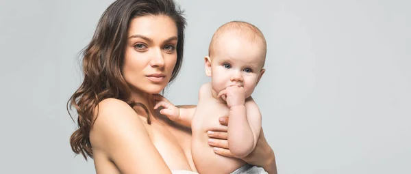Plano panorámico de atractiva madre desnuda sosteniendo bebé niño, aislado en gris - foto de stock