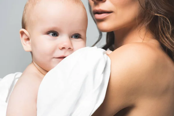 Cropped view of naked mother hugging positive baby boy, isolated on grey — Stock Photo