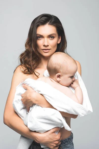 Портрет привабливої голої матері, що тримає хлопчика-немовляти, ізольовано на сірому — стокове фото
