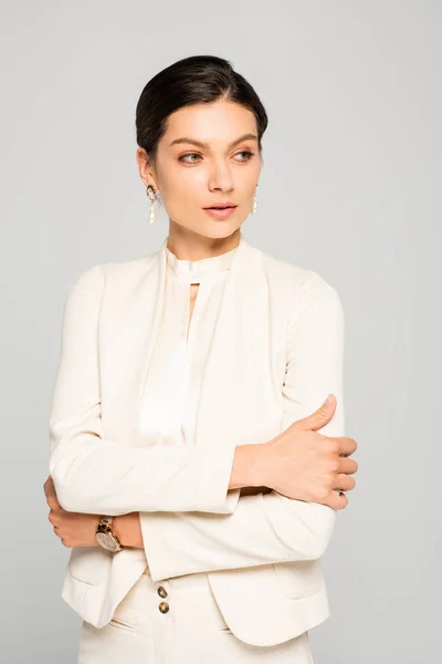 Serious elegant businesswoman with crossed arms in white suit, isolated on grey — Stock Photo