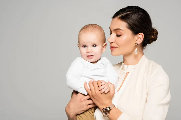 Hermosa joven mujer de negocios con pequeño bebé en las manos, aislado en gris - foto de stock