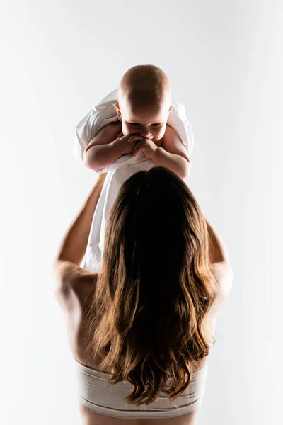 Vue arrière de la silhouette de la mère tenant bébé garçon sur les mains, isolé sur blanc — Photo de stock