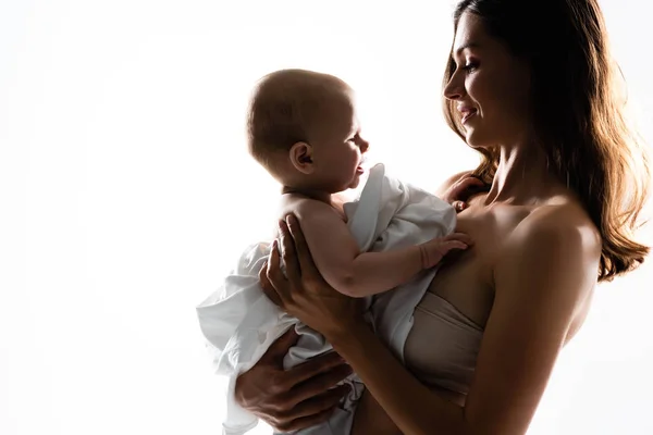 Silueta de madre feliz sosteniendo al niño en las manos, aislado en blanco - foto de stock