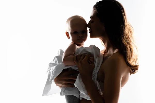 Silueta de la madre sosteniendo al bebé en las manos, aislado en blanco - foto de stock