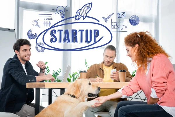 Three friends working and asking paw of cute golden retriever with startup illustration — Stock Photo