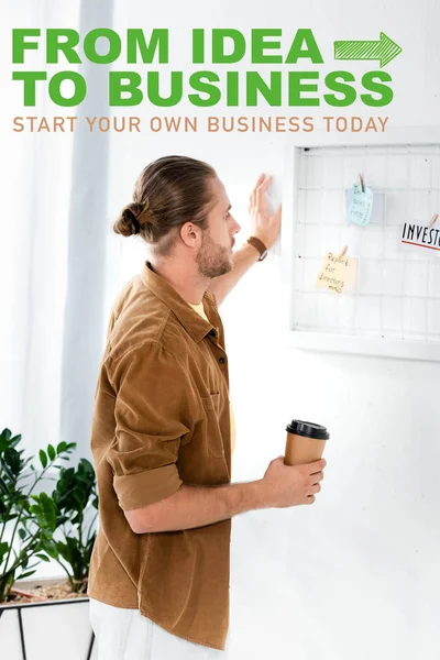 Homem bonito na camisa que olha a placa branca e que prende o copo de papel no escritório com da ideia à ilustração do negócio, conceito da inicialização — Fotografia de Stock