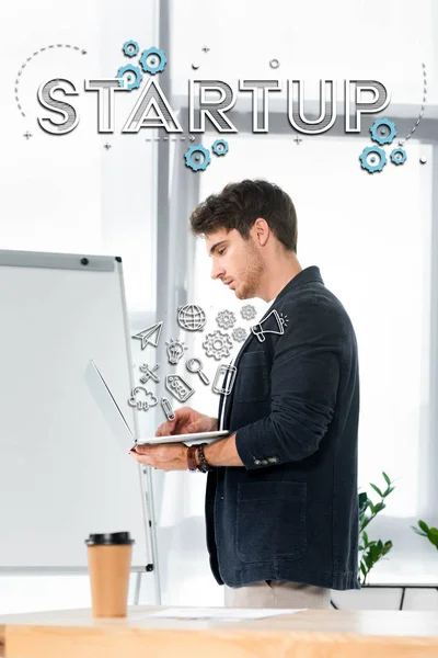 Side view of handsome in shirt using laptop in office with startup illustration — Stock Photo