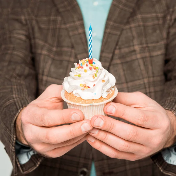 Selective focus of man holding birthday cupcake with candle isolated on grey — Stock Photo