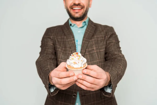 Vue recadrée de l'homme souriant tenant cupcake d'anniversaire isolé sur gris — Photo de stock