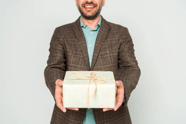 Vista ritagliata dell'uomo sorridente che tiene la scatola regalo isolata sul grigio — Foto stock