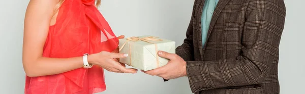 Vista recortada del hombre que presenta caja de regalo a la esposa aislado en gris, plano panorámico - foto de stock