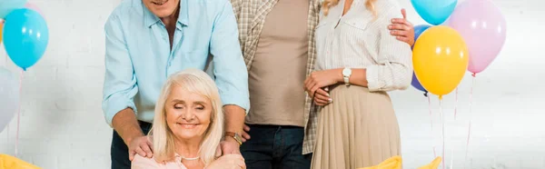 Vista recortada de la mujer mayor feliz sentado en el sofá cerca de la familia - foto de stock