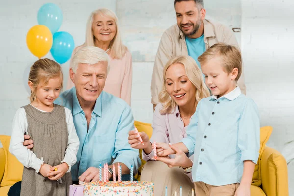 Smiling mother and son holding candles near birthday cake, and family standing around — Stock Photo