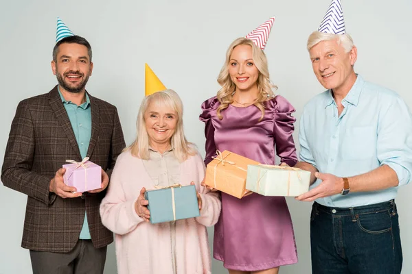 Happy senior parents with adult son and daughter holding gift boxes isolated on grey — Stock Photo