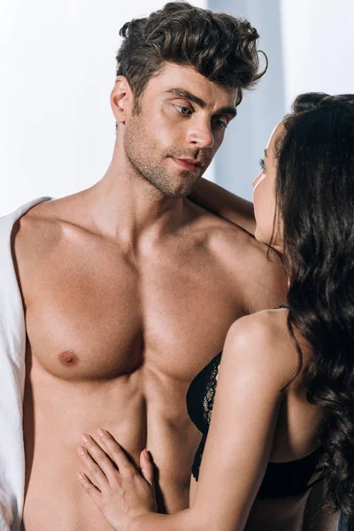 Сексуальный мужчина с мускулистым торсом, смотрящий на девушку в черном белье — стоковое фото
