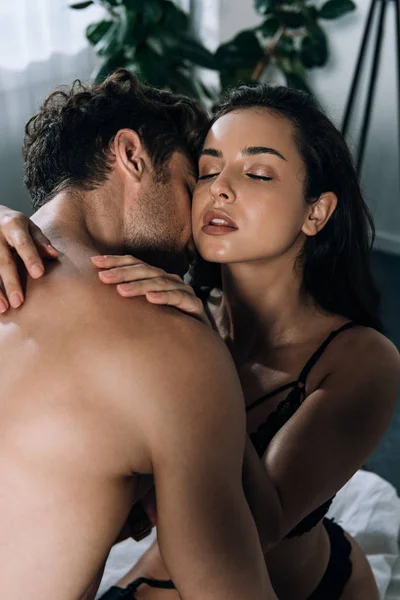 Shirtless man kissing sexy girlfriend embracing him with closed eyes — Stock Photo