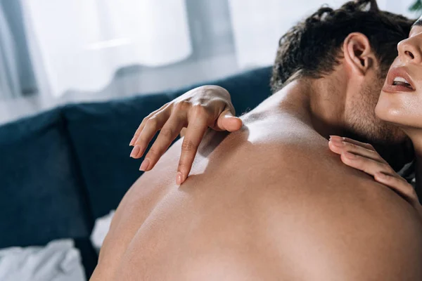 Hemdloser Mann küsst verführerisches Mädchen, während sie seinen Rücken berührt — Stockfoto