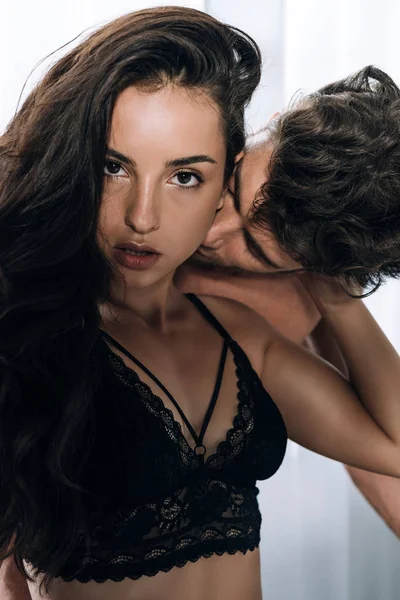 Mulher sexy olhando para a câmera enquanto namorado beijando seu pescoço — Fotografia de Stock