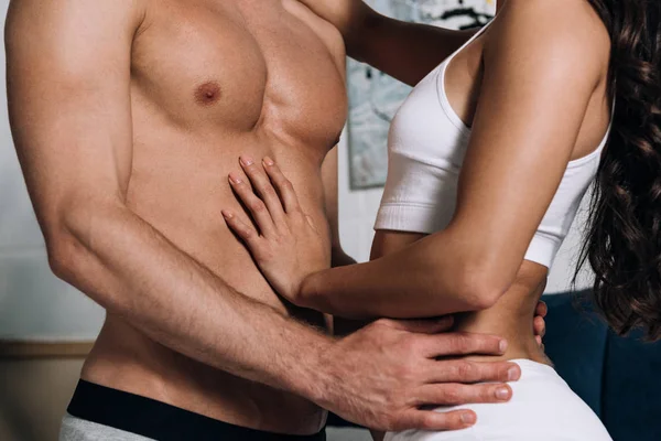 Cropped view of sexy young couple in underwear embracing in bedroom — Stock Photo