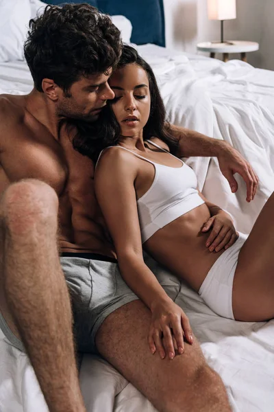 Sexy joven pareja en ropa interior abrazando en la cama — Stock Photo