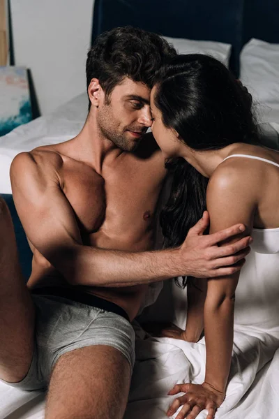 Bel homme en sous-vêtements embrassant femme sexy au lit — Photo de stock