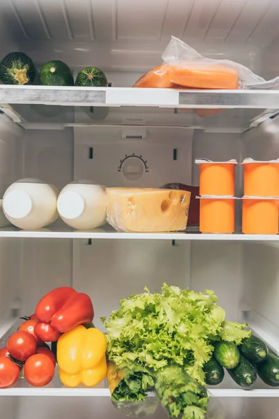 Nevera abierta llena de comida fresca en los estantes - foto de stock